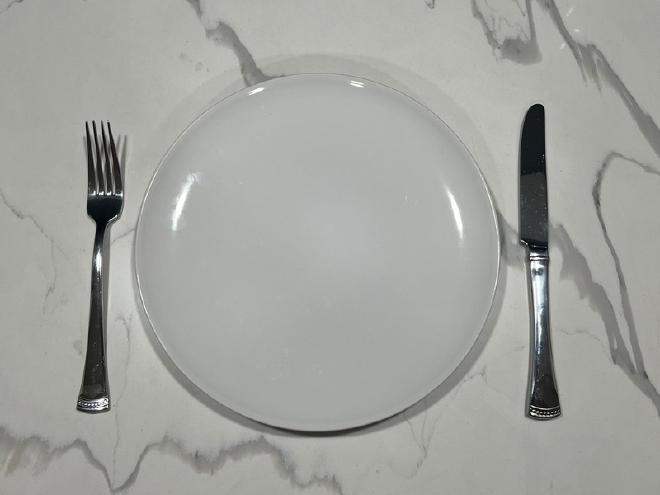 A white plate with a fork and knife on either side.